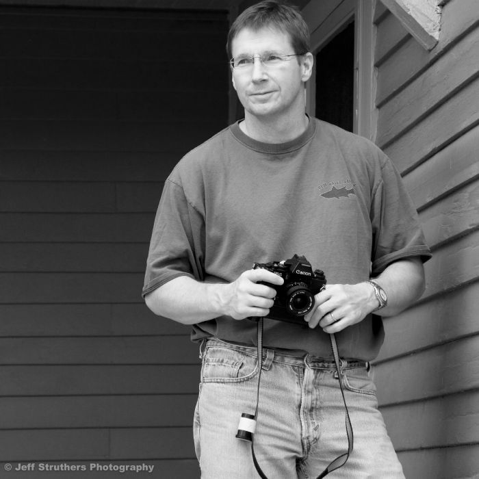 A man holding a camera in front of a building.