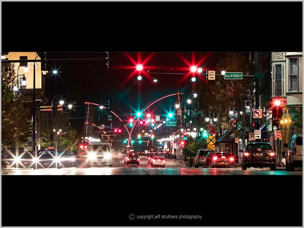 A busy street with traffic lights and cars at night.