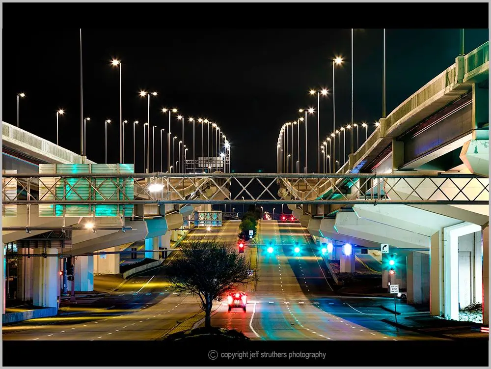 A night time photo of an overpass and roadway.